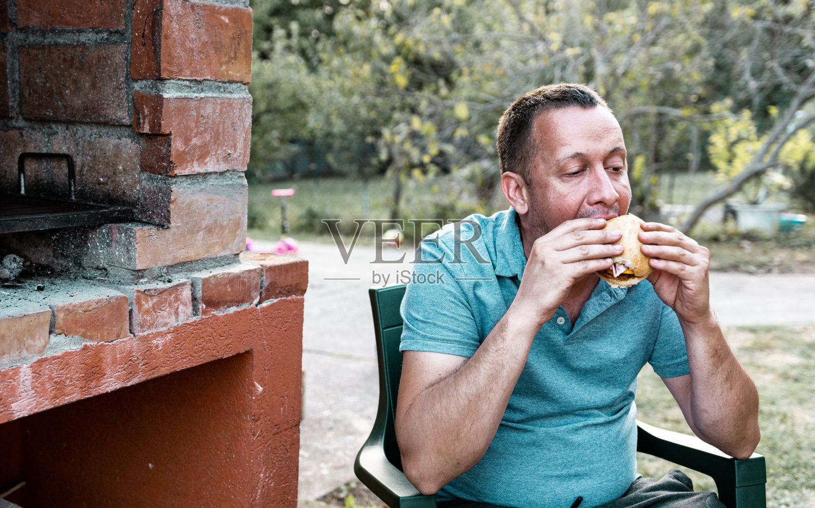一个男人在院子里吃汉堡照片摄影图片
