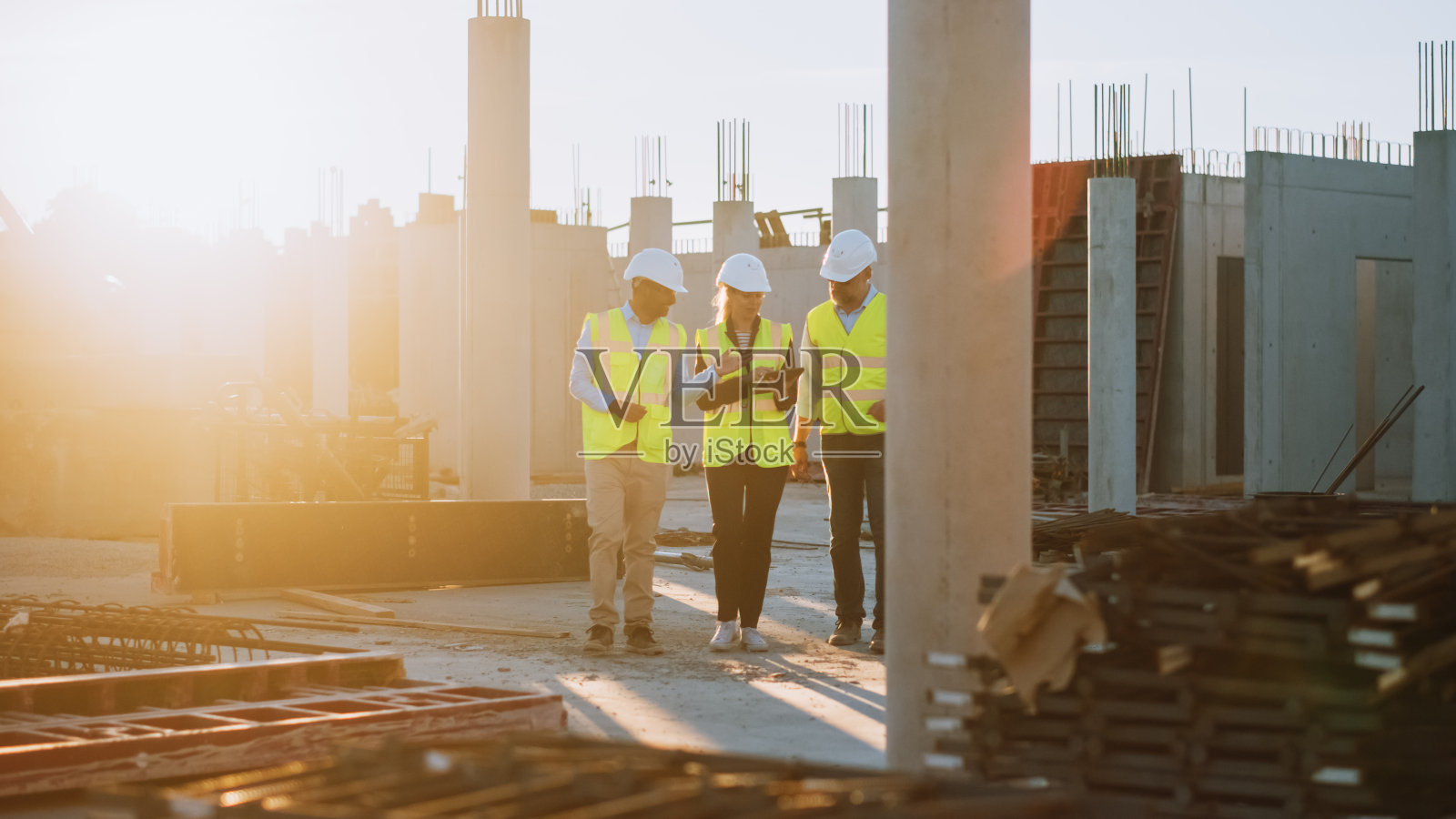 多元化的专家团队在建筑工地漫步。房地产建设项目与高级土木工程师,建筑师,一般工人讨论规划和发展细节。照片摄影图片