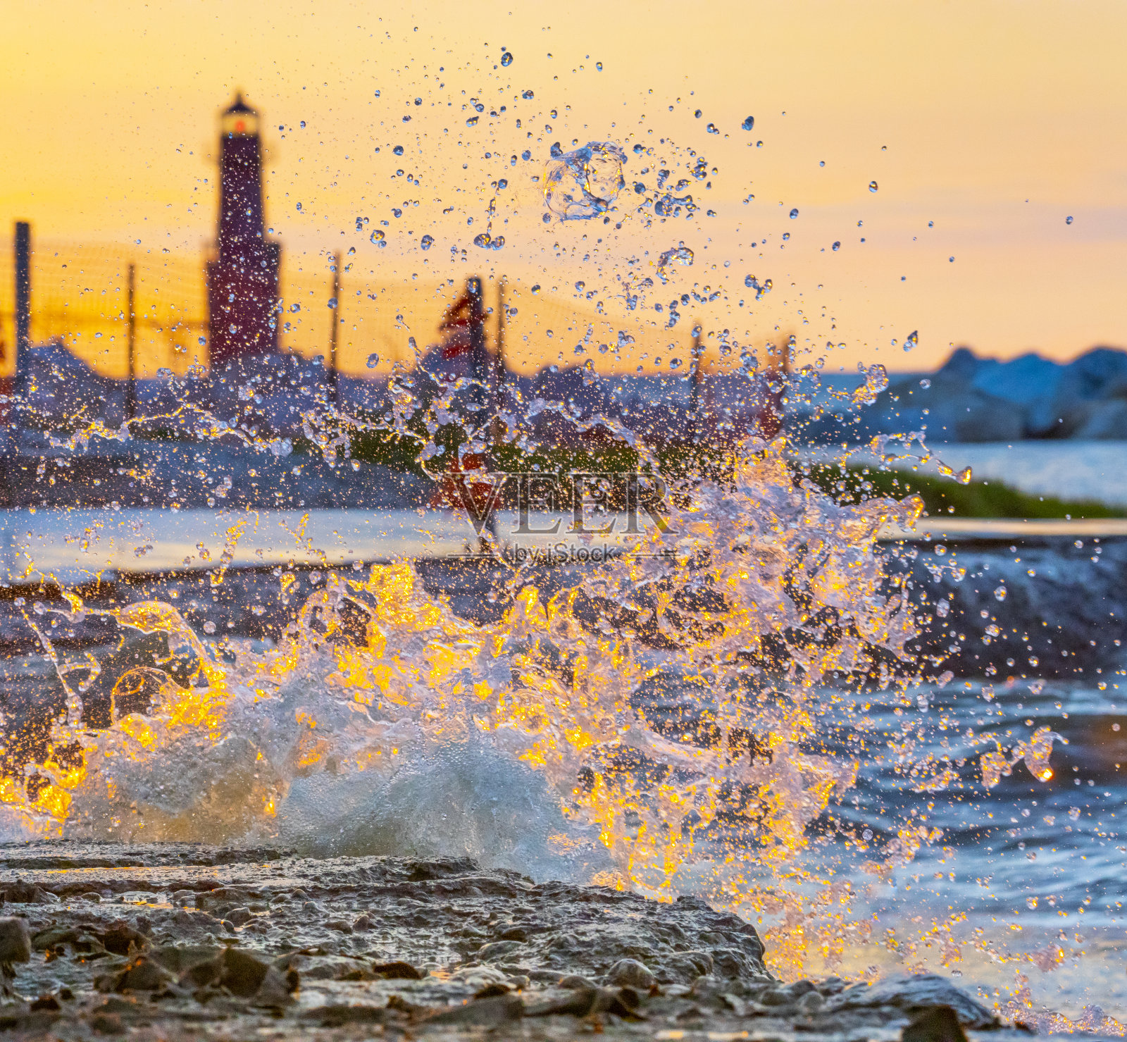 溅起的浪花被黎明的阳光照亮照片摄影图片