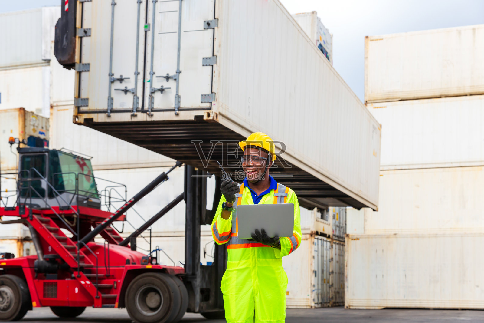 工头控制空运或海运。工头用笔记本电脑无线电与叉车司机沟通。照片摄影图片