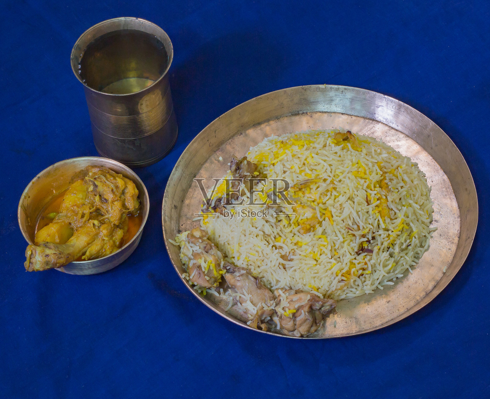 美味的印度香鸡饭与咖喱鸡一起盛在黄铜盘子里。照片摄影图片