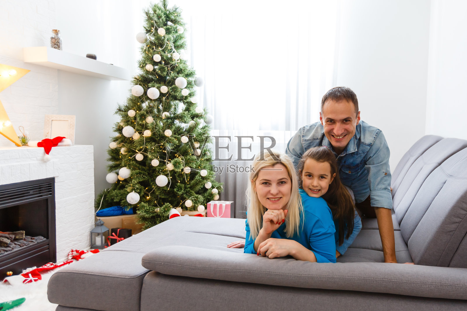 年轻的家庭在圣诞节早上交换礼物,享受他们在一起的时间。照片摄影图片