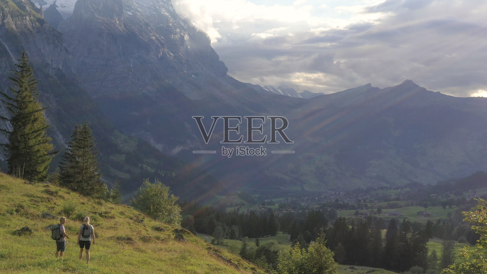 鸟瞰图的徒步旅行夫妇穿越高山草地,在日出照片摄影图片