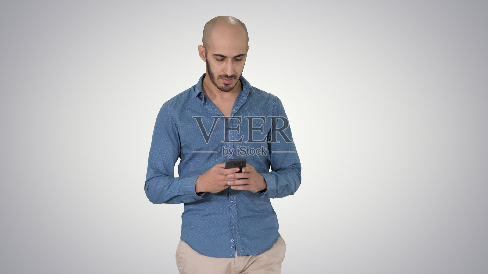 男人在渐变背景上行走时发短信照片摄影图片