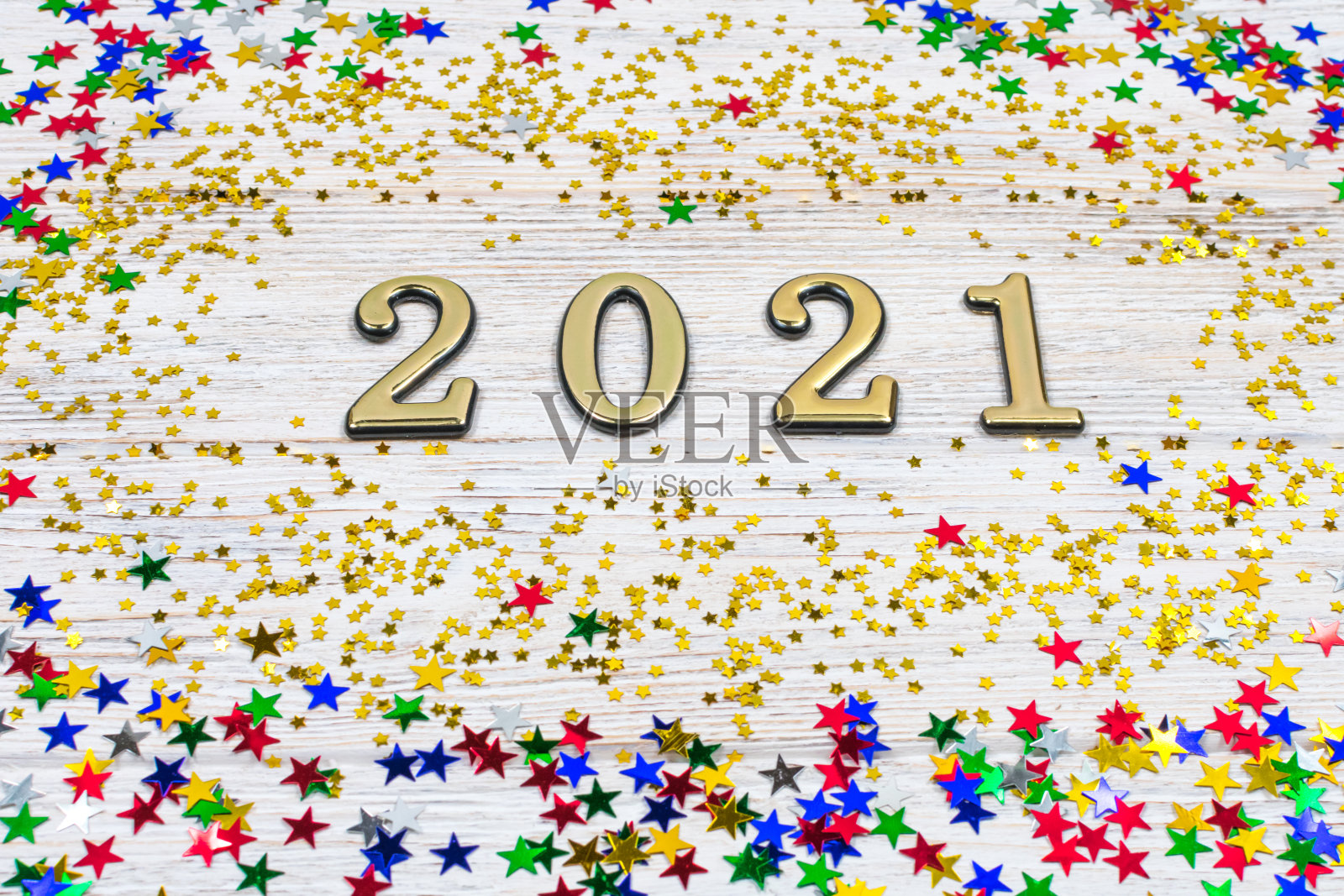 金色数字2021被金色和彩色星星围绕在浅色木质背景上。新年的象征。2021年新年庆祝活动。照片摄影图片