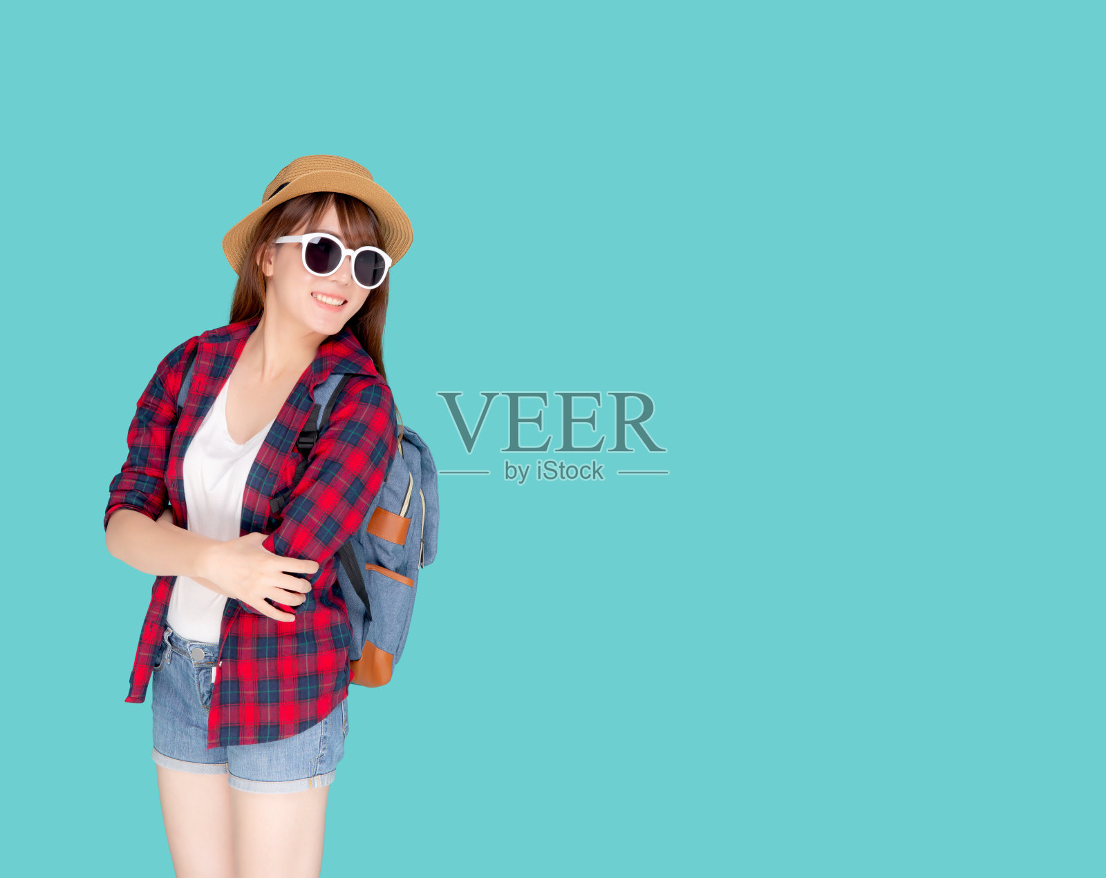 美丽的肖像年轻的亚洲女人戴太阳镜和帽子微笑兴奋和自信享受暑假孤立的蓝色背景,模特女孩开朗有背包度假,旅游概念。照片摄影图片