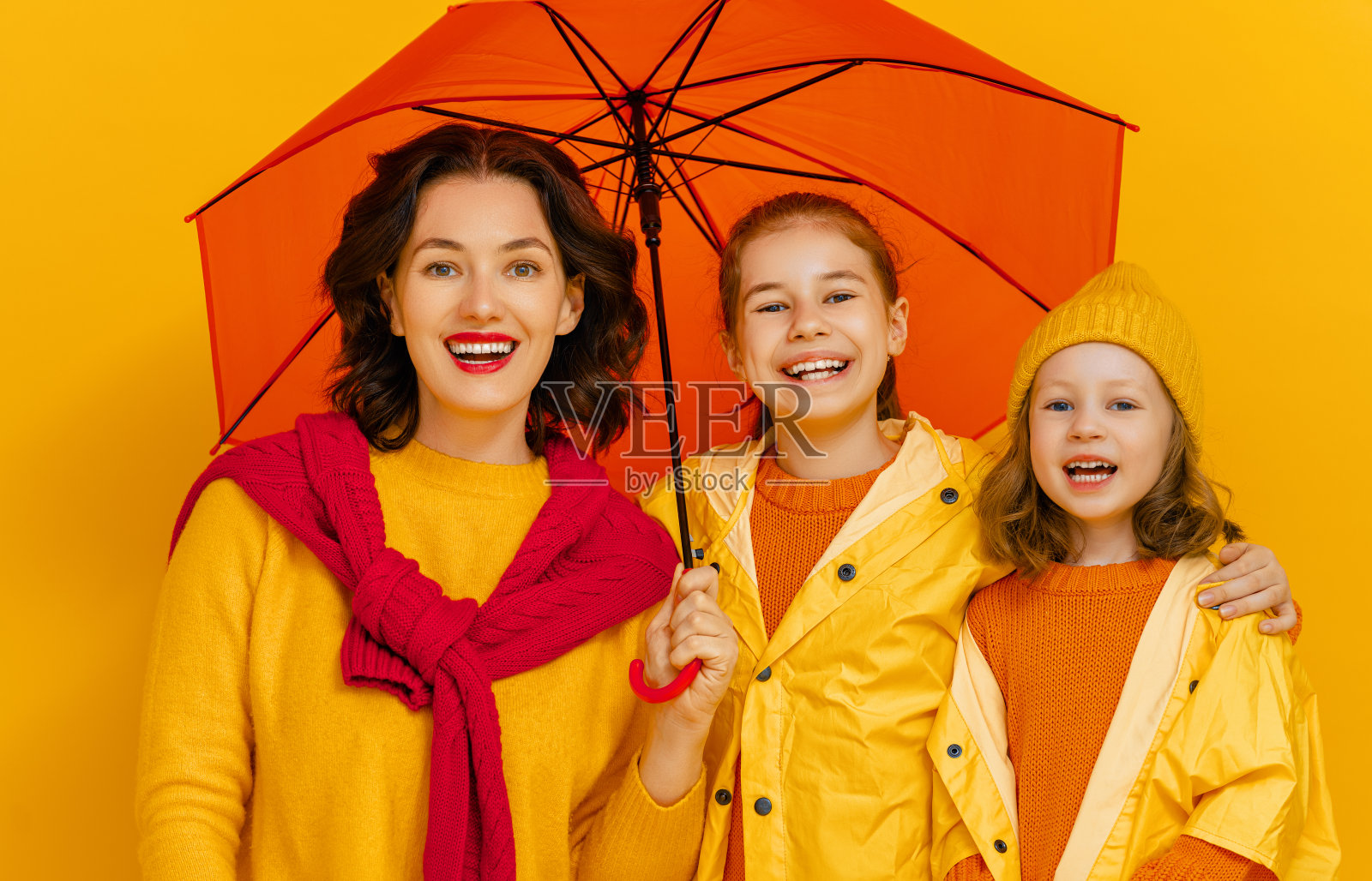 彩色背景上带伞的家庭。照片摄影图片