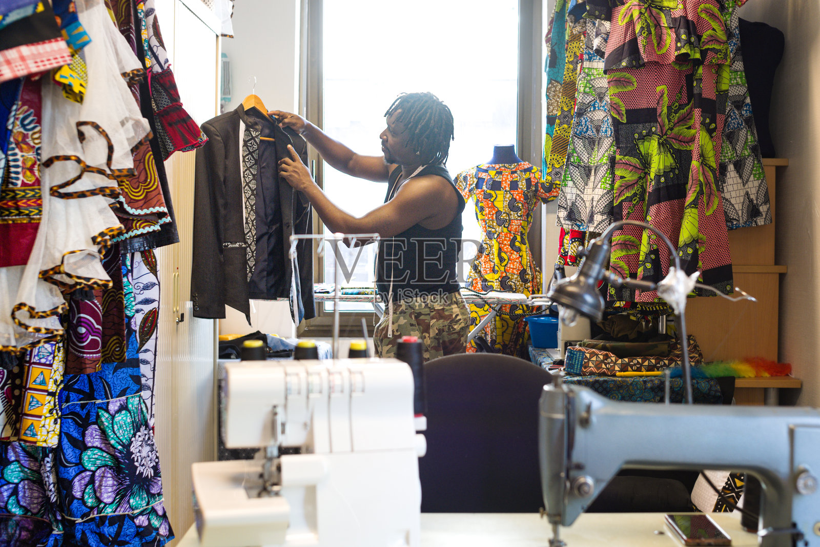 一位时装设计师在他的工作室里整理一件夹克照片摄影图片