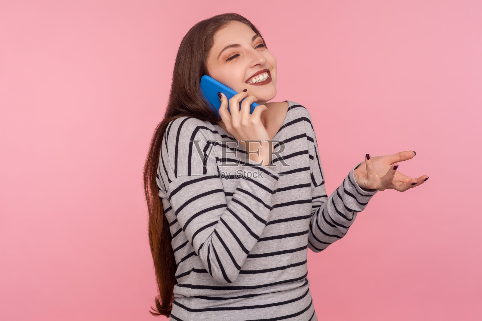 移动通信。肖像快乐的女人在条纹运动衫微笑愉快而打电话照片摄影图片