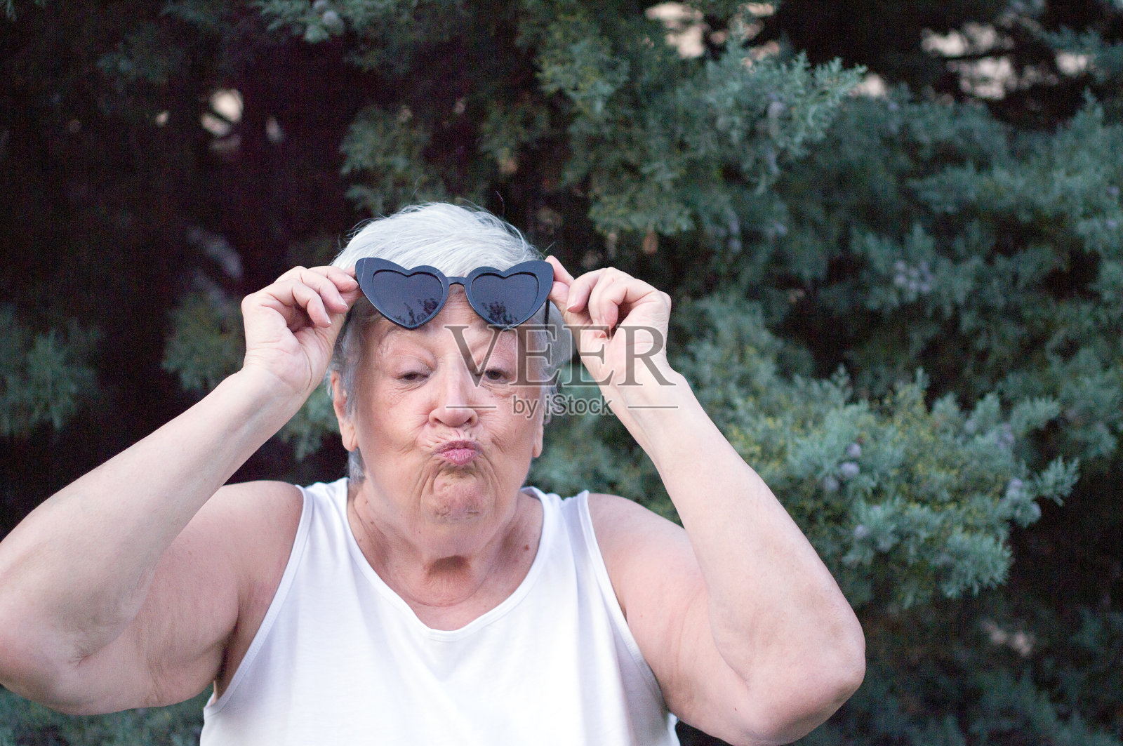 年长的女人看着镜头做了一个接吻的手势。照片摄影图片