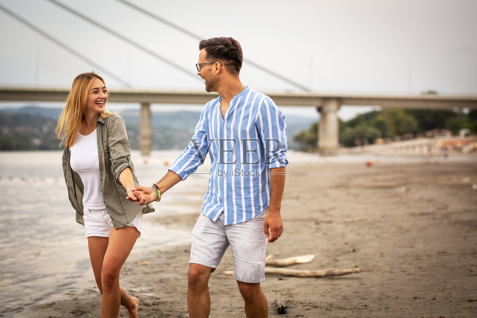 一对幸福的情侣在城市海滩上闲逛。照片摄影图片