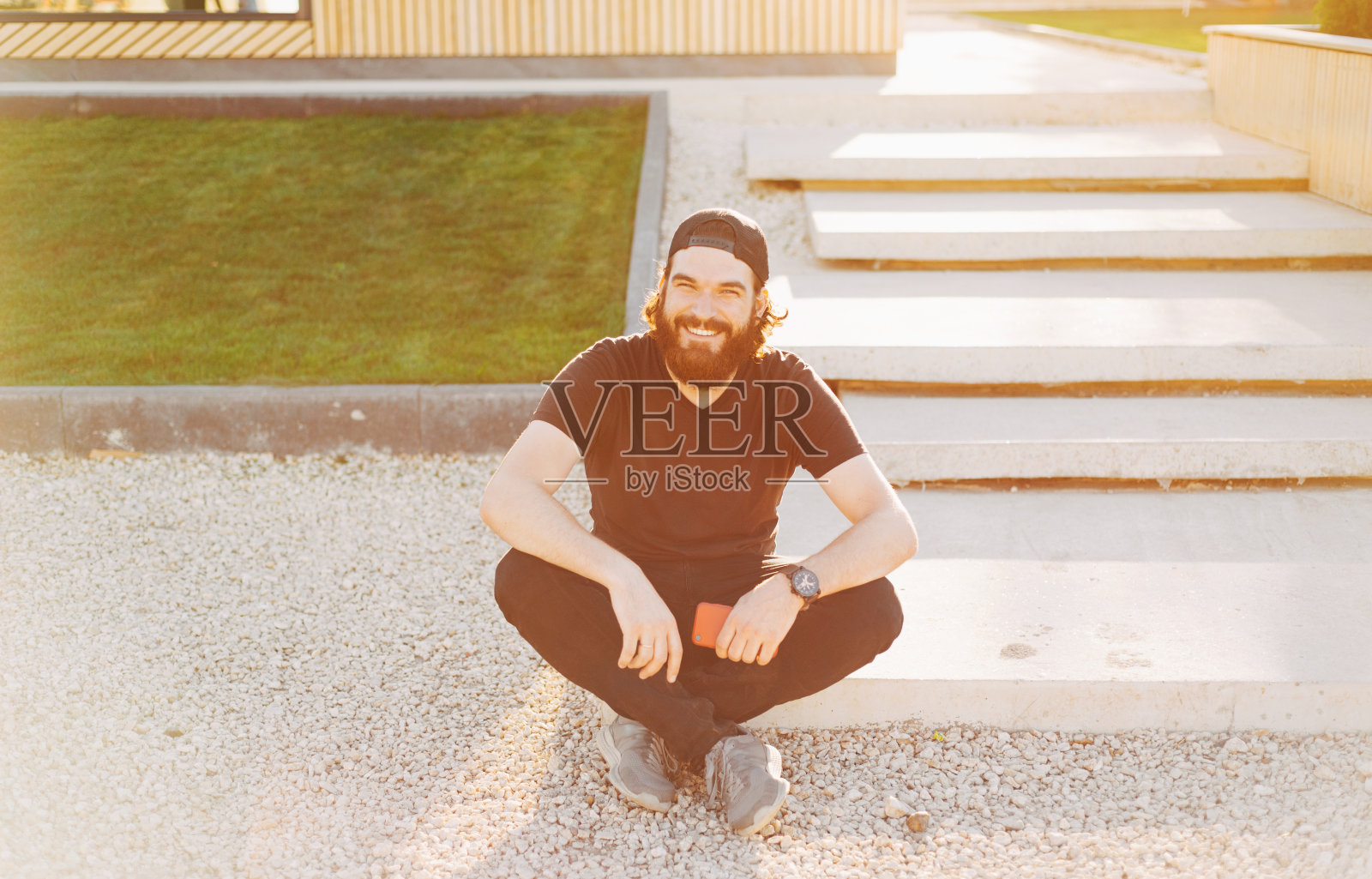 一名蓄着胡须的年轻男子在一所新房子附近对着镜头微笑照片摄影图片