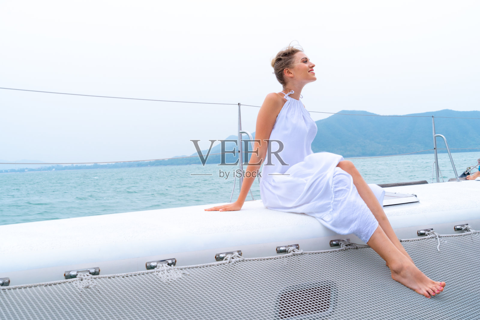 豪华放松的女孩旅行者在漂亮的衣服和套房坐在一部分的游轮上与大海和白色的天空的背景。商务旅行概念。照片摄影图片