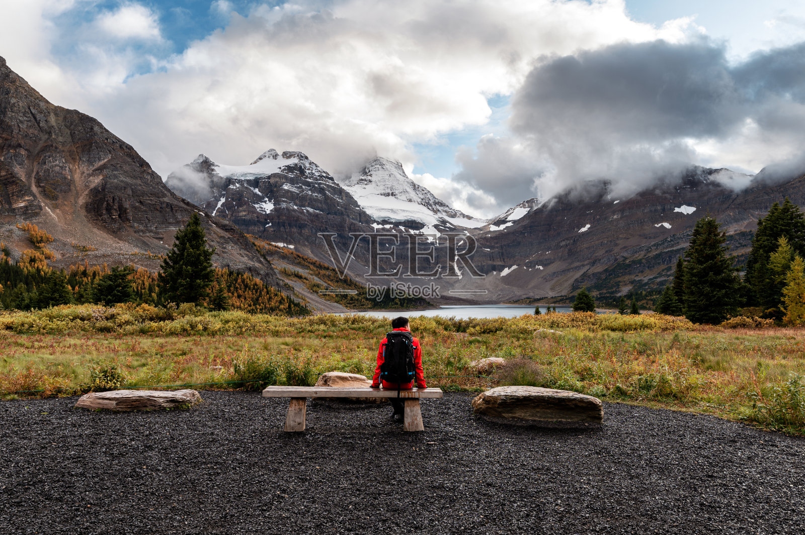 旅行者坐在海滩上,与阿西尼博因山和马戈格湖在省级公园照片摄影图片