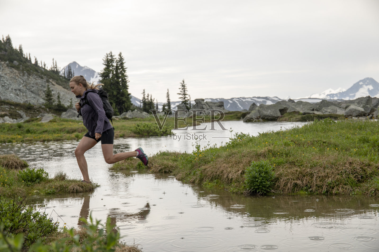 女性徒步旅行者跳过湖泊浅滩照片摄影图片