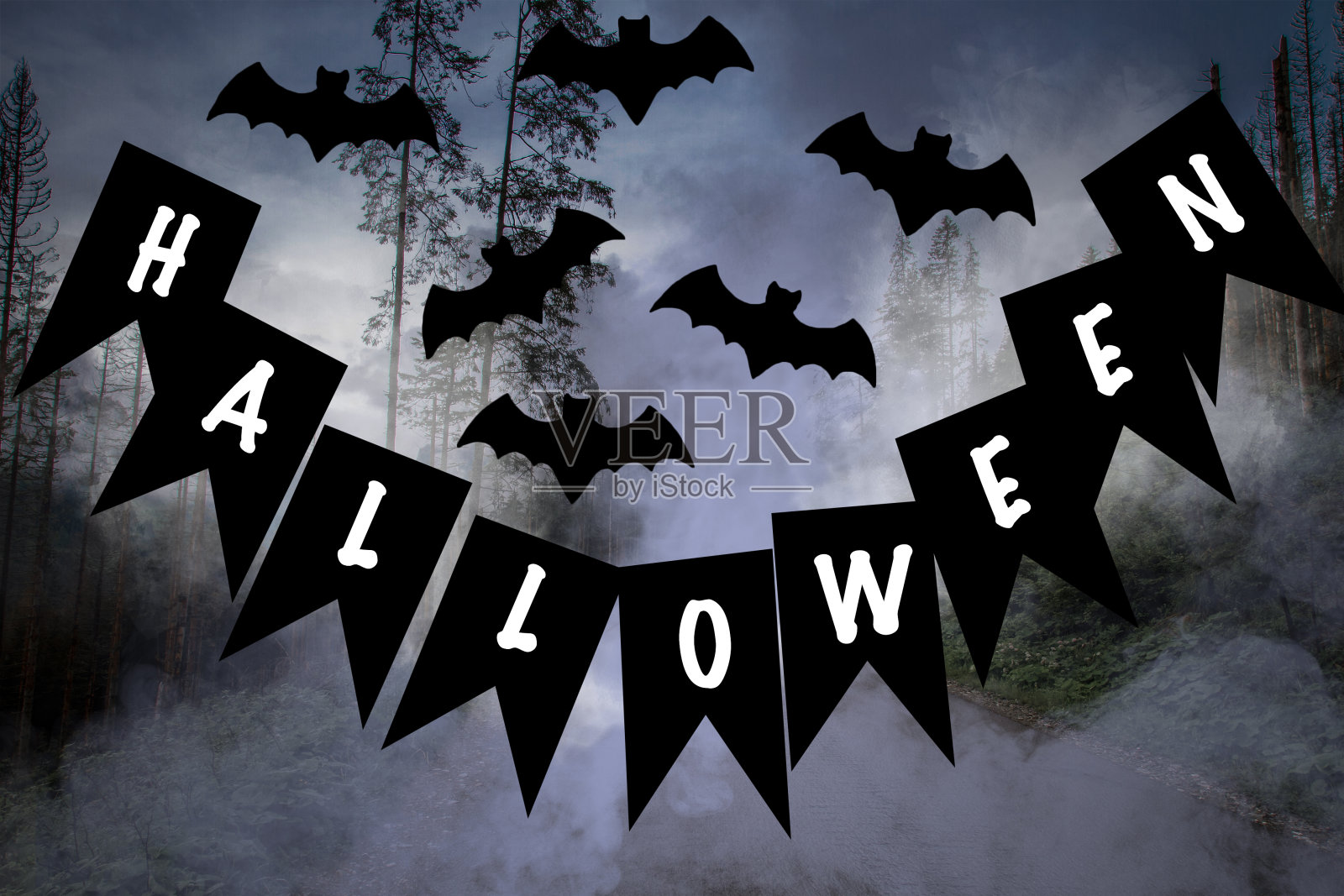 黑色旗帜上的万圣节字样。附近是蝙蝠的雕像。在森林和烟雾后面。照片摄影图片