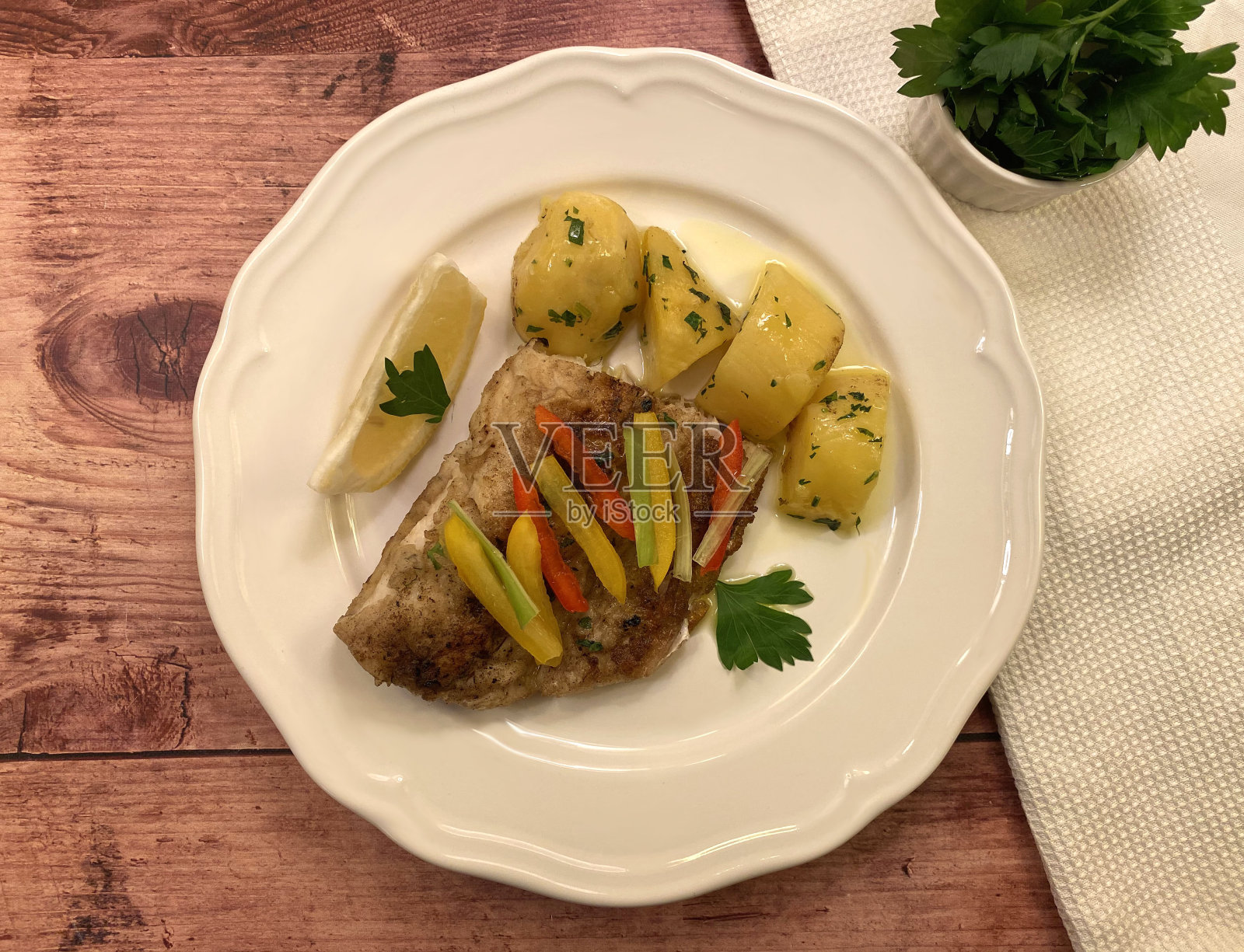 梭鱼鲈鱼片配欧芹土豆烧烤。照片摄影图片