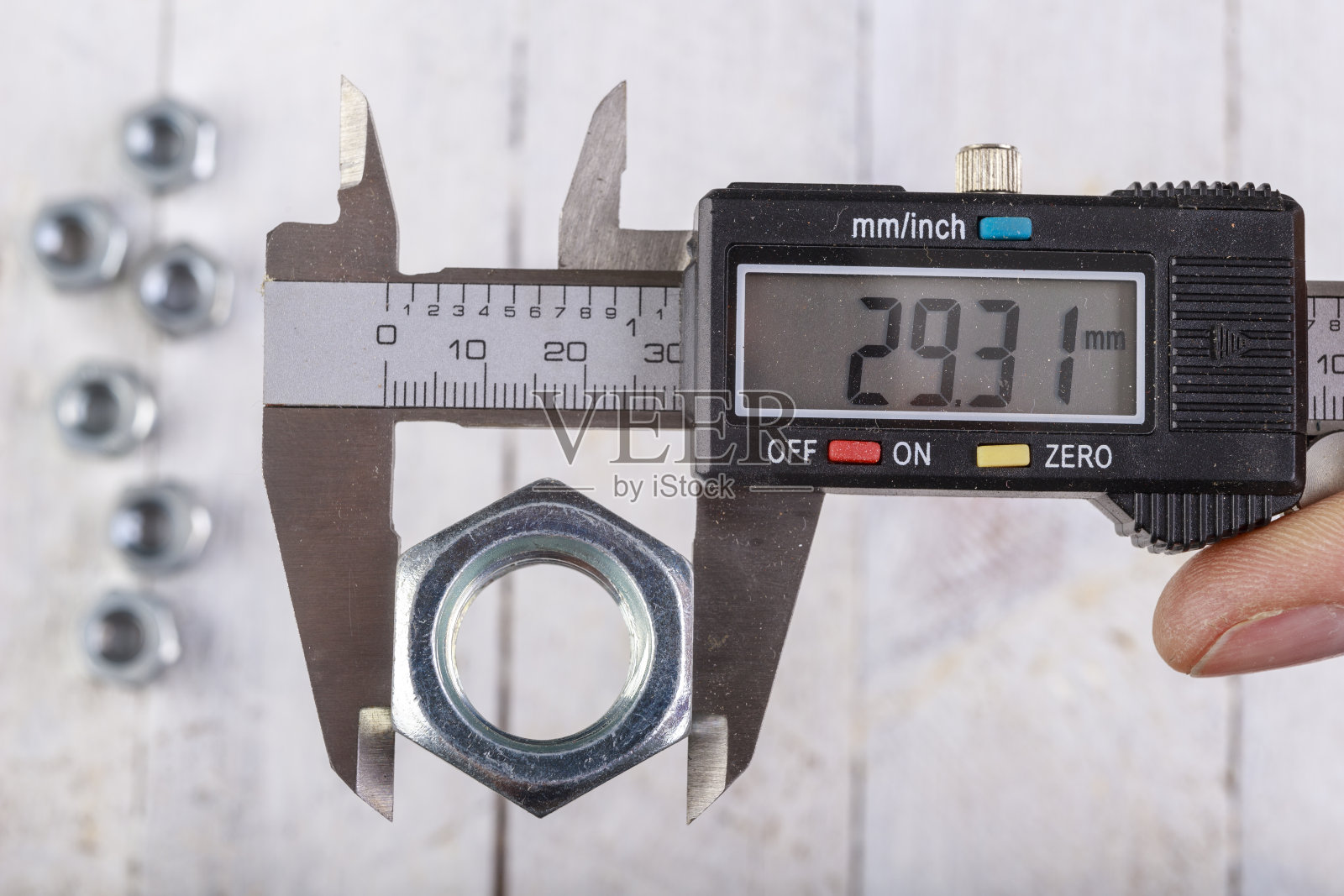 用电子卡尺测量螺母宽度。在家庭车间测量配件。光背景。照片摄影图片