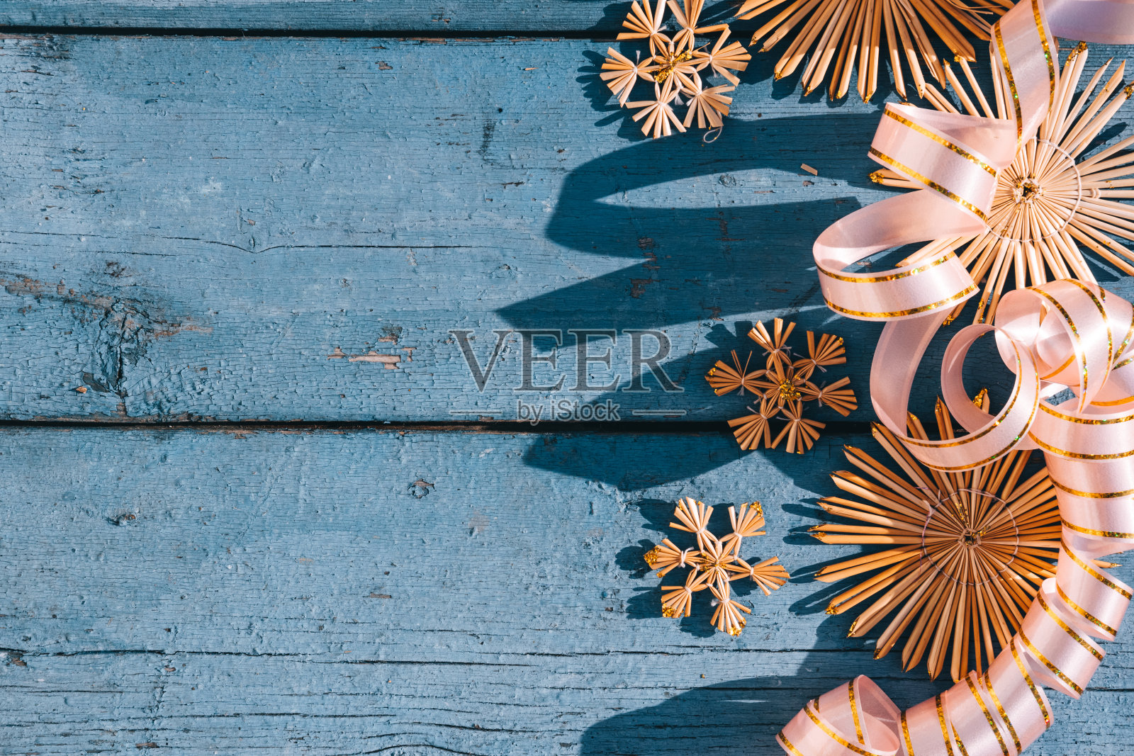 木制圣诞背景,俯视图。放置文字在新年的背景。美丽的蓝色圣诞背景草雪花和粉红色的丝带。照片摄影图片