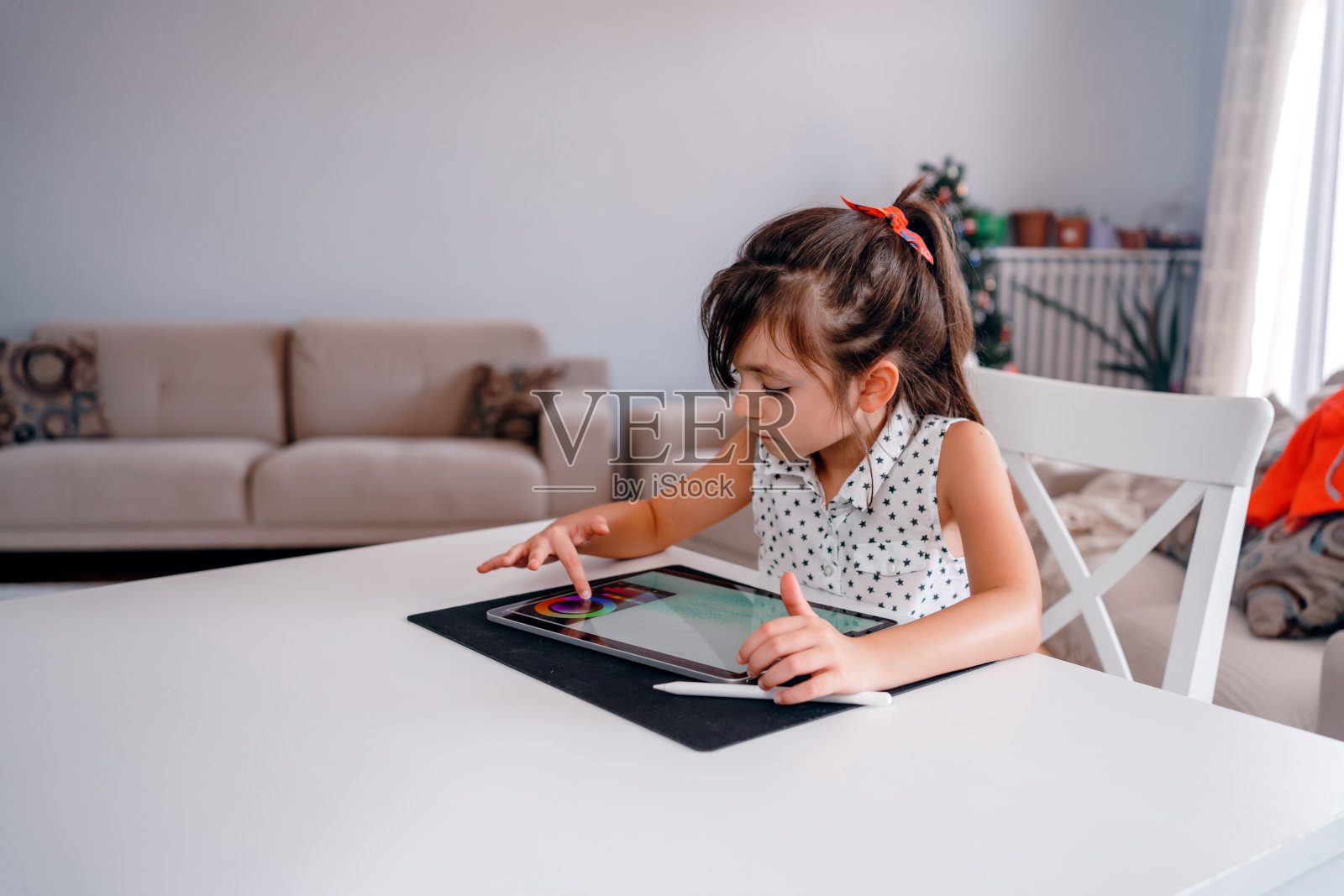 聪明的青春期前女学生在家用平板电脑做家庭作业。使用小工具学习的孩子照片摄影图片