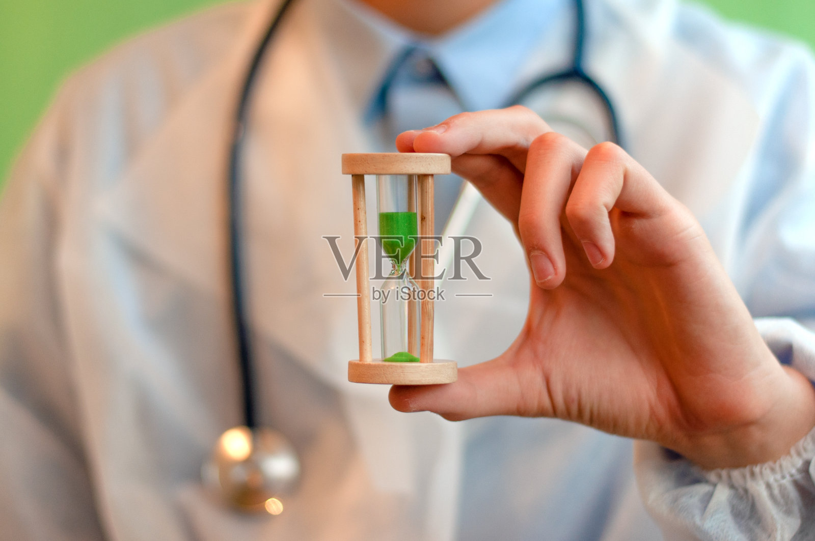一位戴着白色医用手套的医生手持一个沙漏,象征着治愈和治愈的时间。近距离照片摄影图片