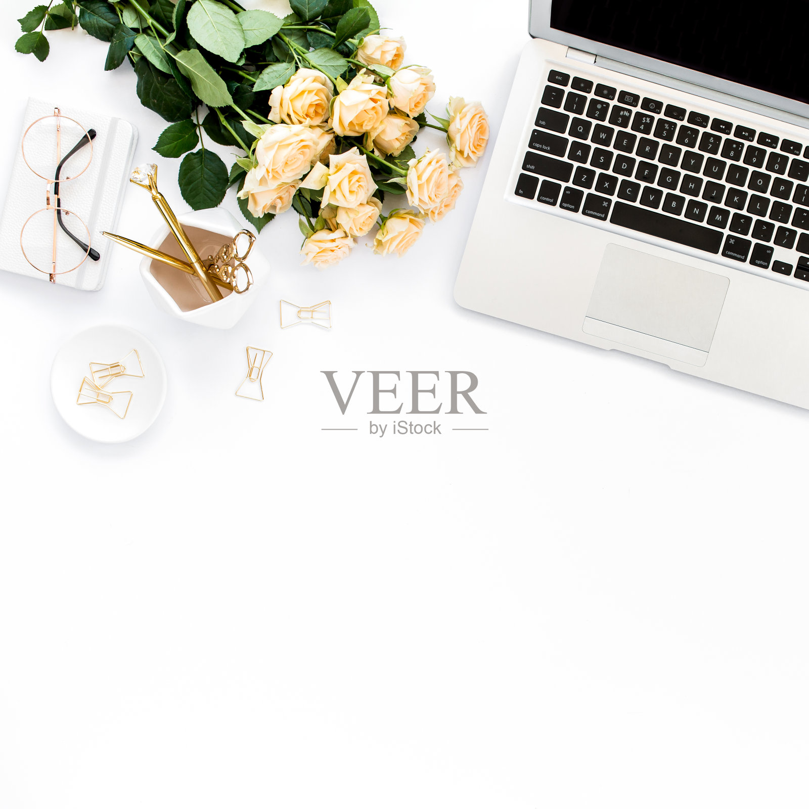 女性的工作空间有笔记本电脑,玫瑰花,金色的配件,日记,电脑,白色背景的眼镜。平放的女性办公桌。俯视图照片摄影图片