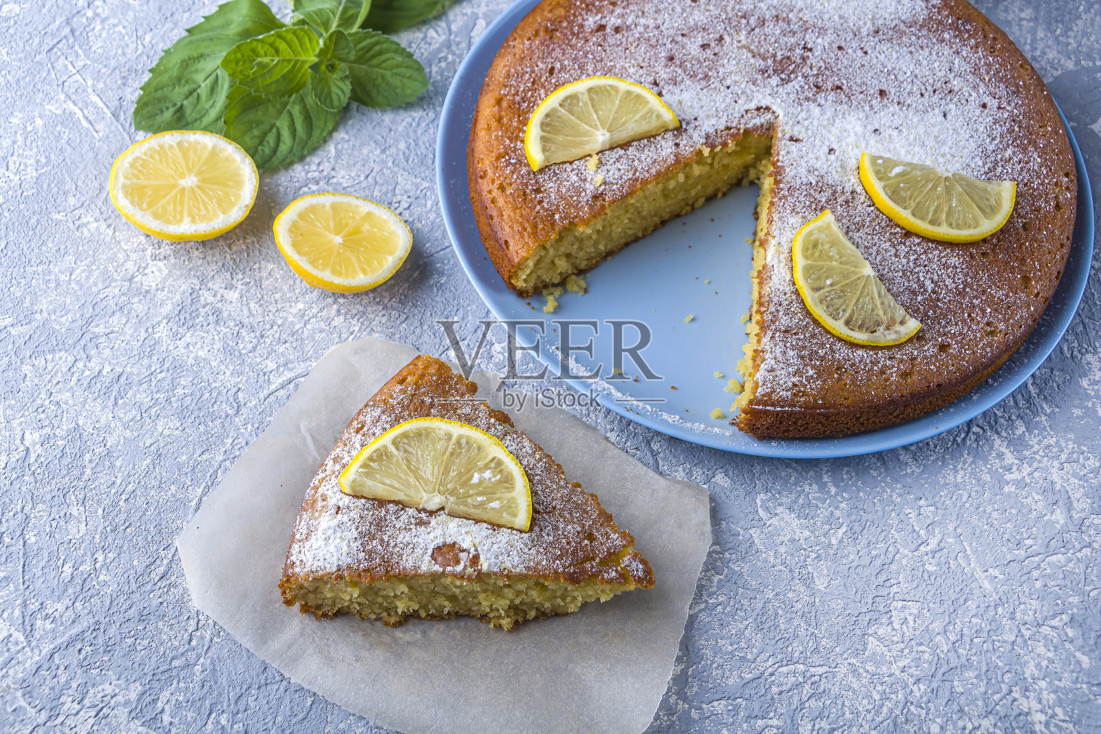 将新鲜出炉的柠檬派、馅饼或粗麦粉蛋糕切成片,盛在盘子里,配上柠檬角和薄荷。自制烘焙。关闭,为文本复制空间照片摄影图片