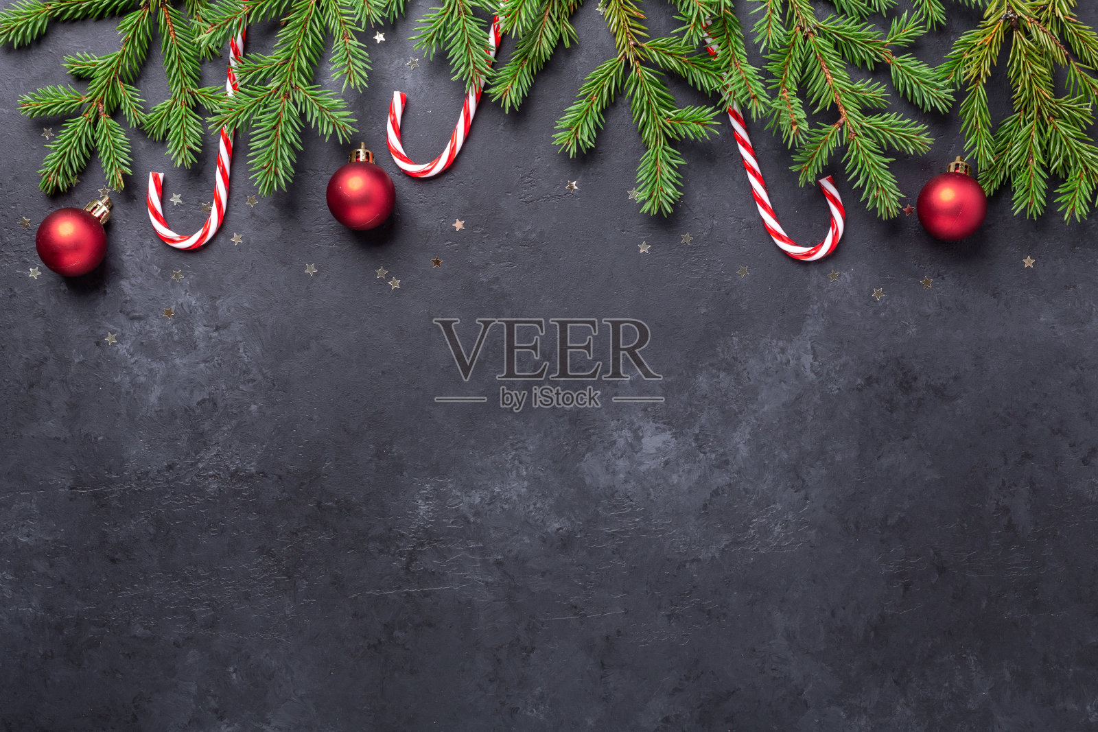 圣诞背景与冷杉树,冬青和红色球在黑暗的石头背景。拷贝空间照片摄影图片