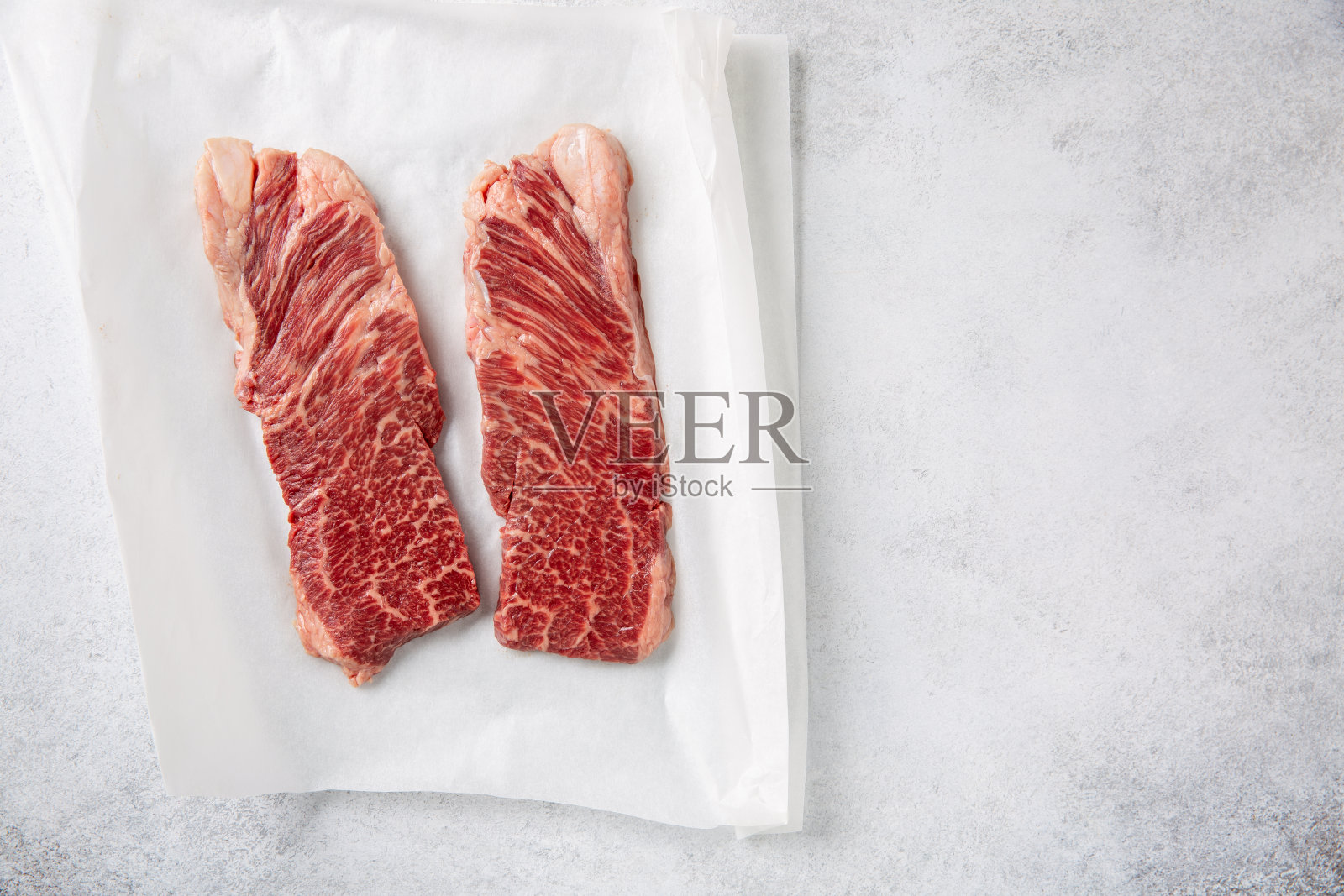 丹佛牛排。纸上的两块生牛排,背景是混凝土。俯视图,复制空间。照片摄影图片