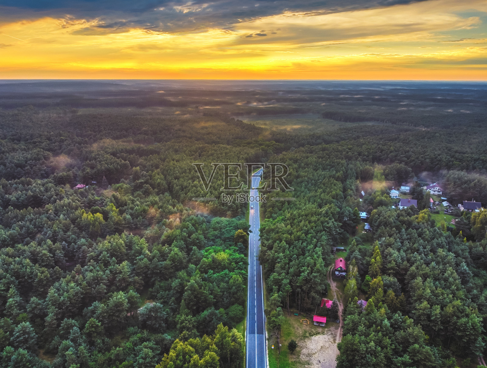夕阳西下时,道路的高处景色消失在森林中。无人机,鸟瞰图。照片摄影图片