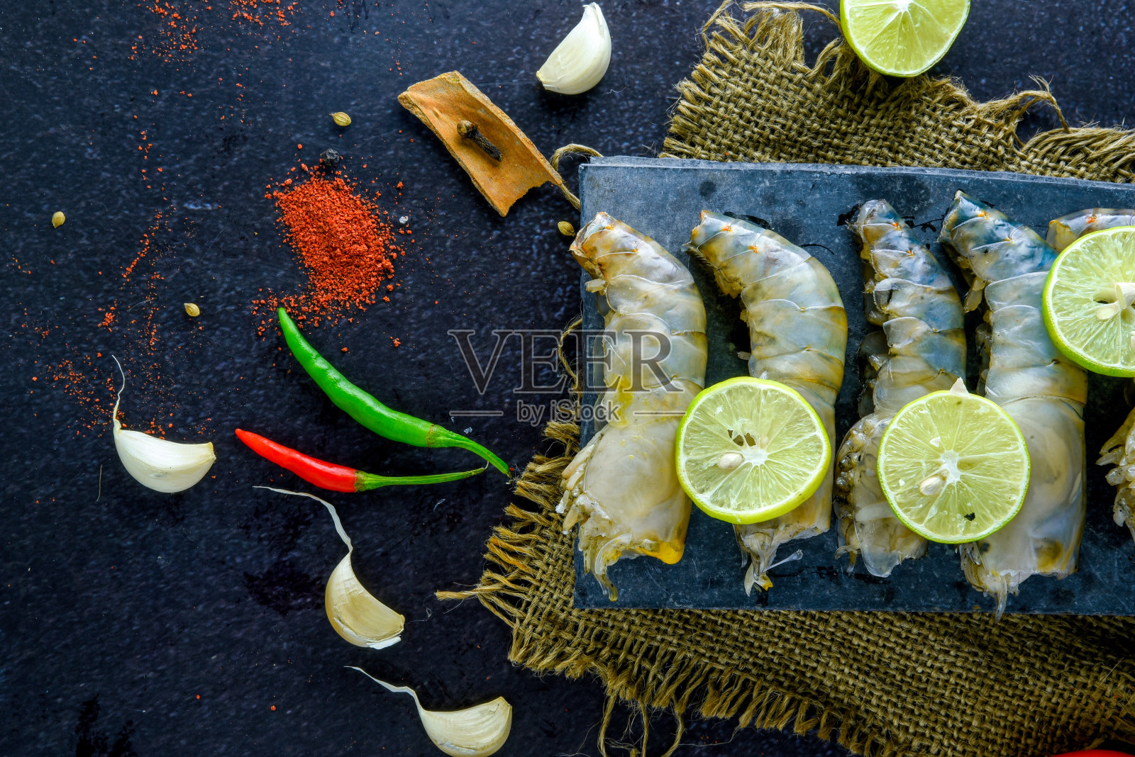 生虾放在木砧板上/鲜虾对虾在海鲜餐厅的深色背景上加香料,柠檬照片摄影图片