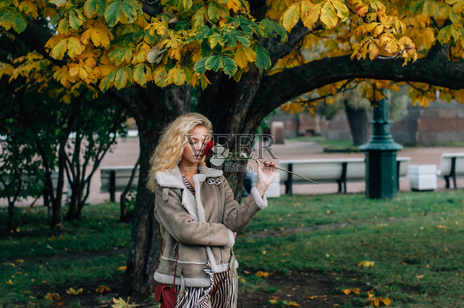 年轻的金发女孩闭着眼睛呆在公园的树附近照片摄影图片