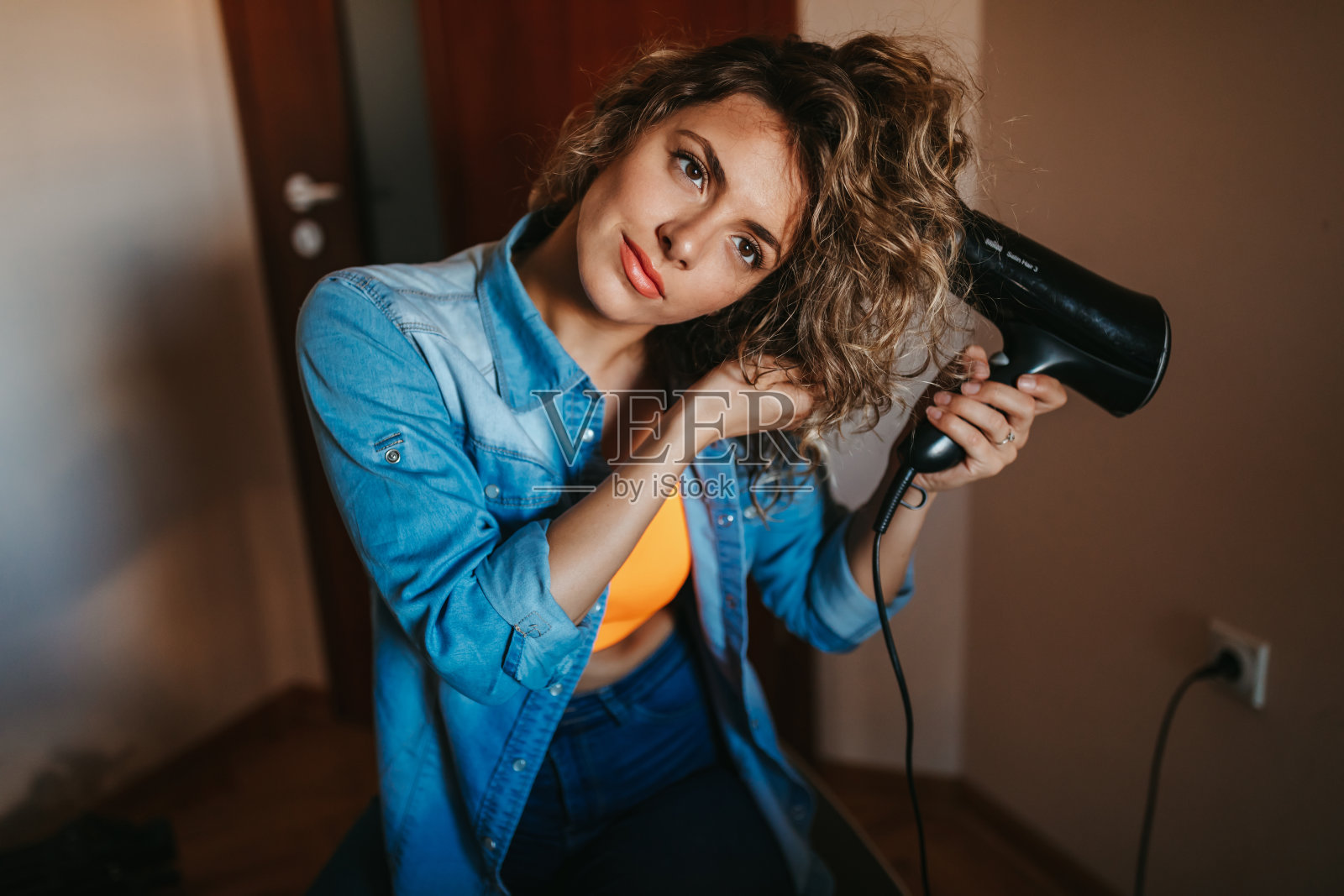 年轻女子用电吹风吹干头发照片摄影图片