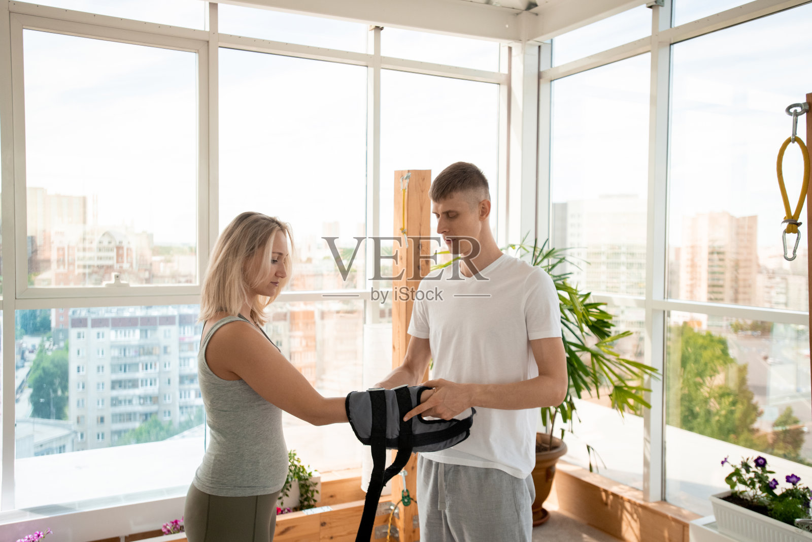 年轻的瑜伽教练穿着运动服,把特殊的设备放在女性手腕上照片摄影图片