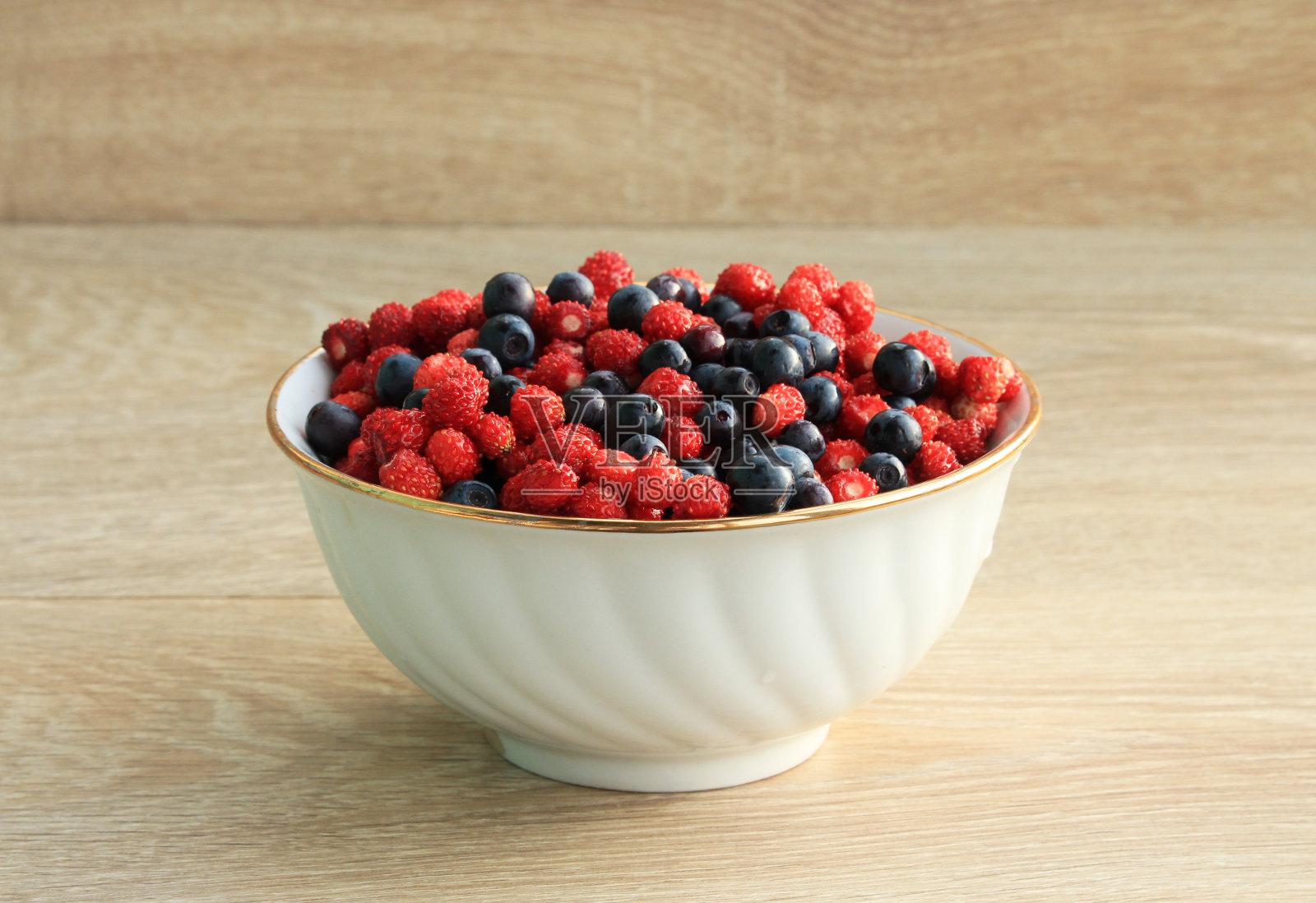 白色陶瓷盘子里装着草莓和蓝莓照片摄影图片