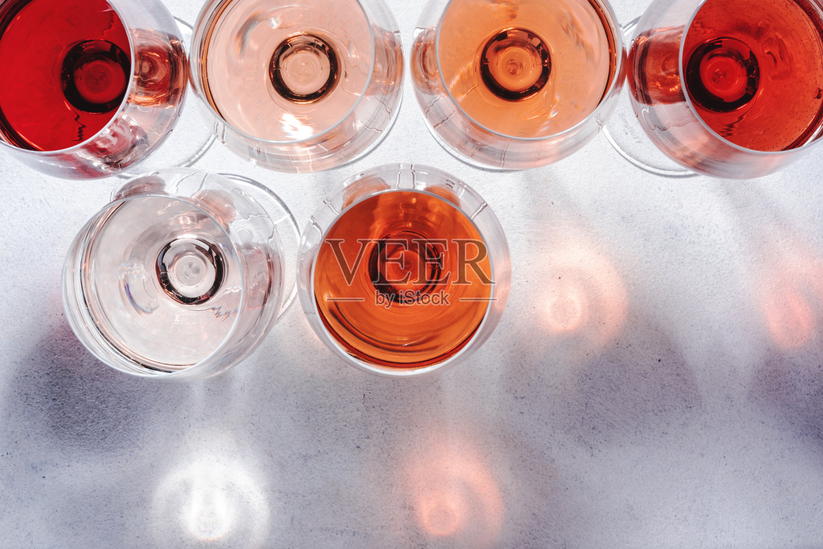 玫瑰色酒杯上的葡萄酒品尝。品尝不同品种、颜色和深浅的粉红葡萄酒概念。白色背景,俯视图照片摄影图片