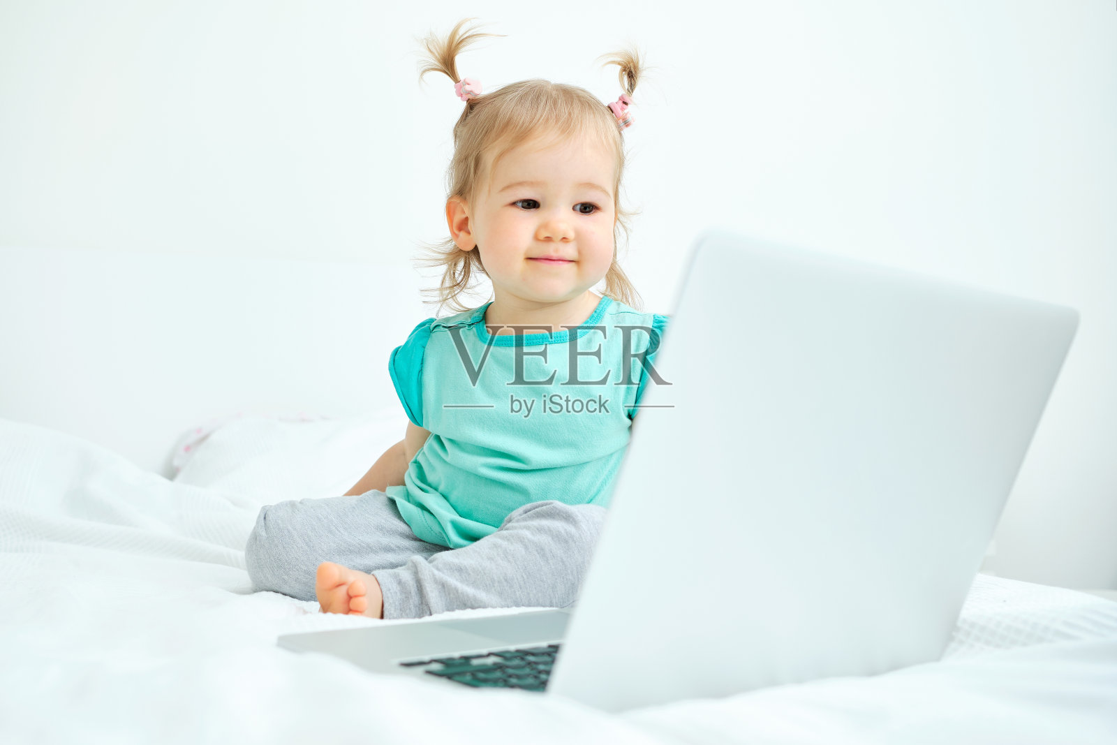 快乐微笑的白人小女孩看着笔记本电脑照片摄影图片