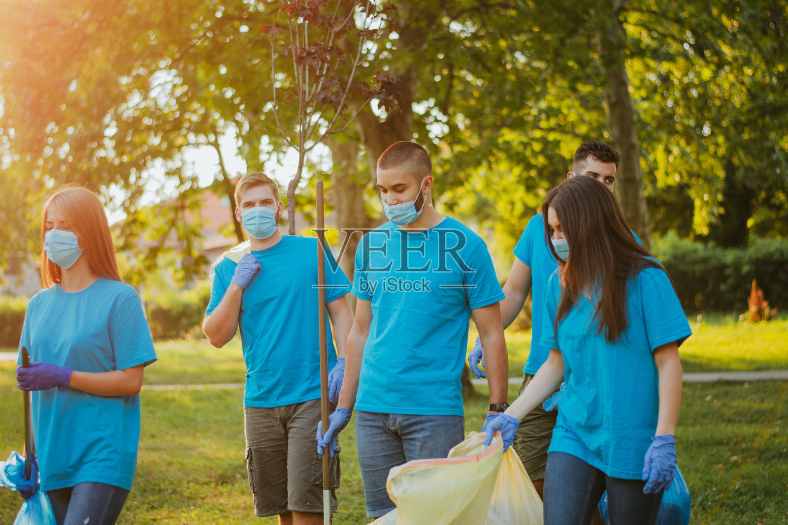 一群青年志愿者带着外科口罩一起清洁大自然照片摄影图片