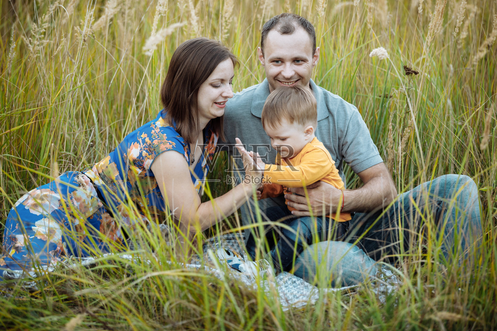 快乐的家庭在户外草地上玩耍。一家人在牧场一起享受生活。妈妈,爸爸,小男孩在户外度过空闲时间时微笑着照片摄影图片