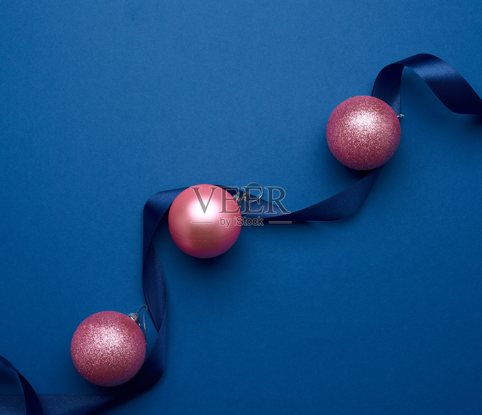蓝色背景上的丝带和粉色闪亮的圣诞球照片摄影图片