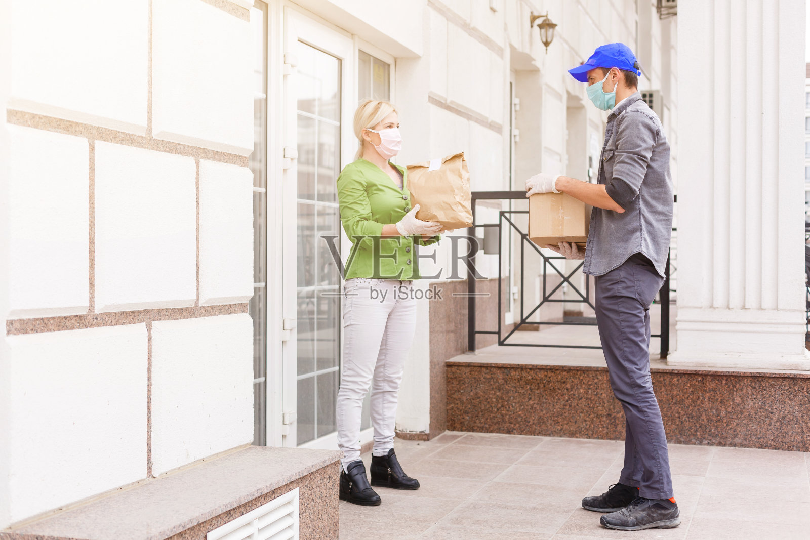 快递员带着防护口罩和医用手套送外卖。隔离、疾病爆发、冠状病毒新冠肺炎大流行情况下的配送服务。照片摄影图片