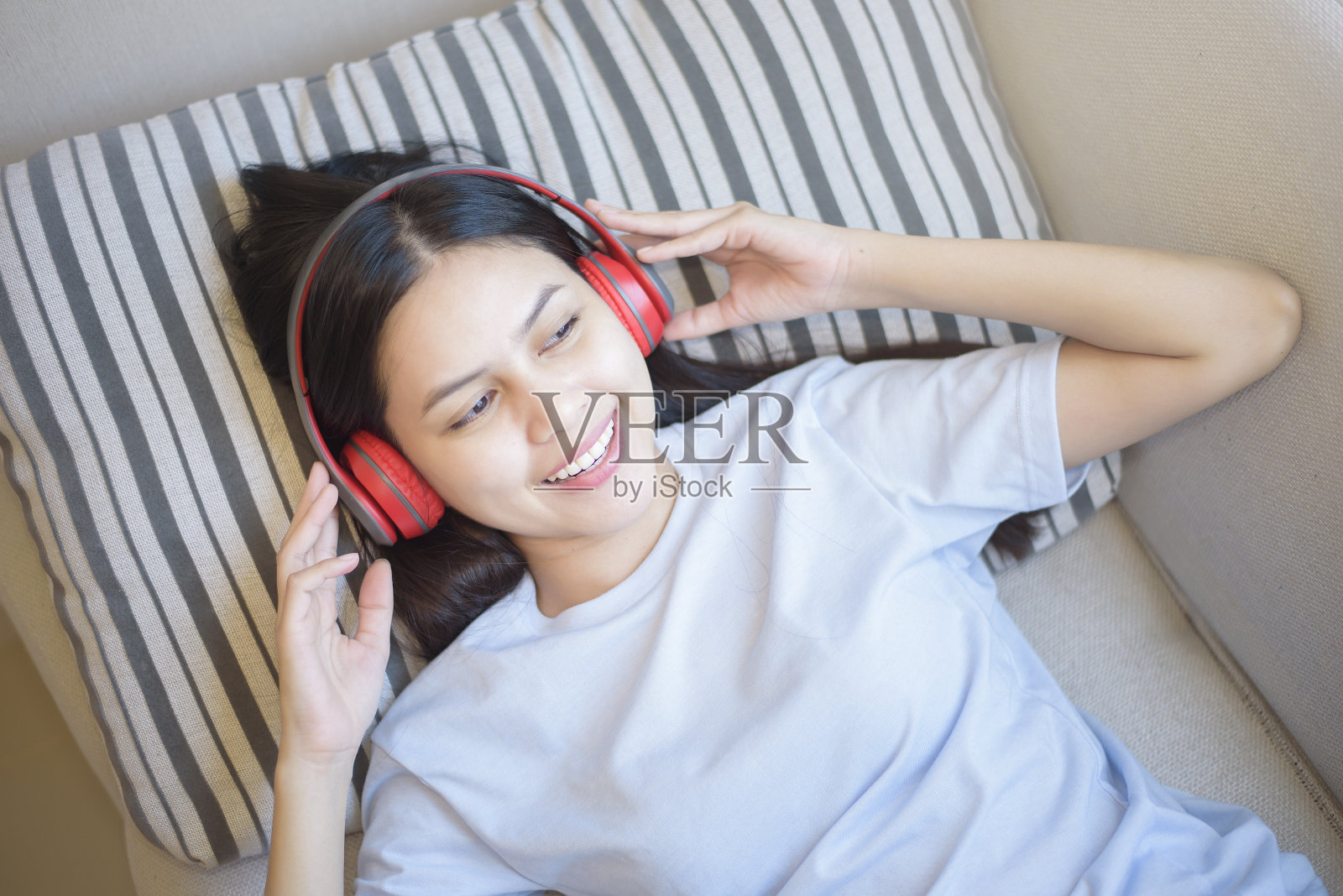 一名年轻女子正在客厅用耳机欣赏音乐,家居安全理念照片摄影图片