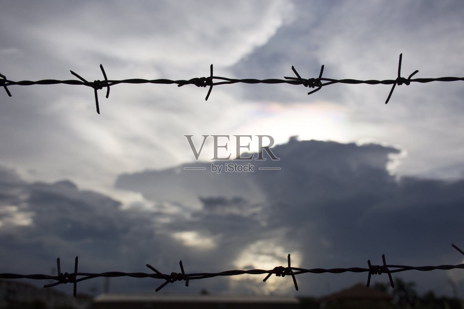 在傍晚时分,蔬菜园农场周围的金属铁丝网与云景天空隔开照片摄影图片