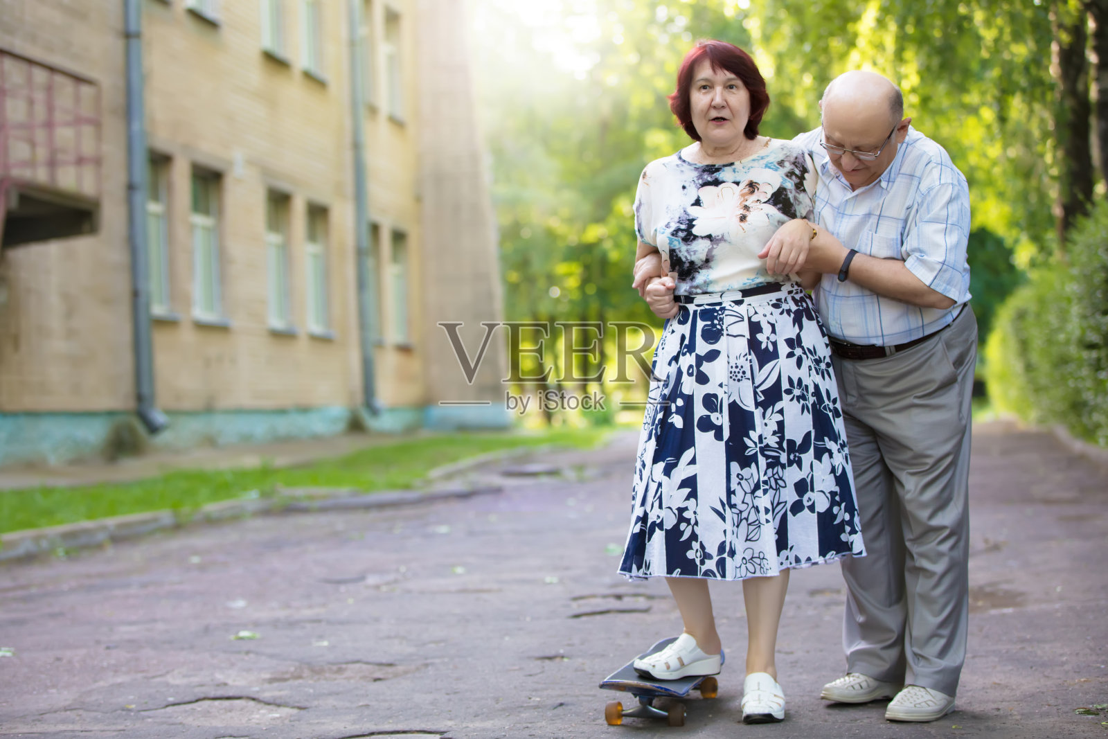 一对玩滑板的快乐老夫妇。英俊的男女老人。年老的夫妻在城市里散步。照片摄影图片