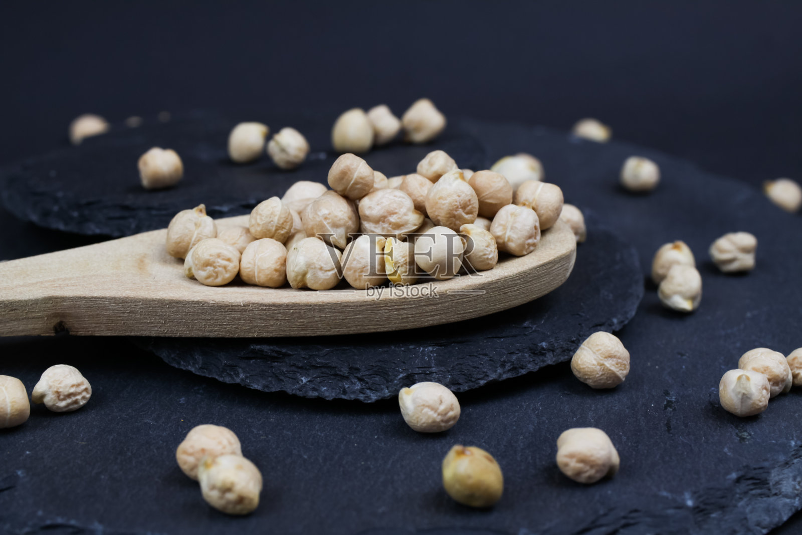 微距特写孤立的木勺与生鹰嘴豆(channa dhal)在黑色石板石背景照片摄影图片