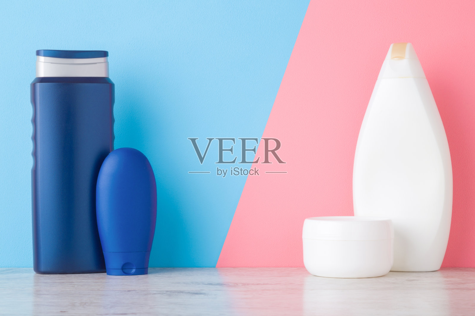 瓶,管和罐在架子上淡蓝色粉红色的墙背景。柔和的颜色。关心脸、手、腿和身体皮肤。男女美容产品。文字或标识的空白位置。前视图。照片摄影图片