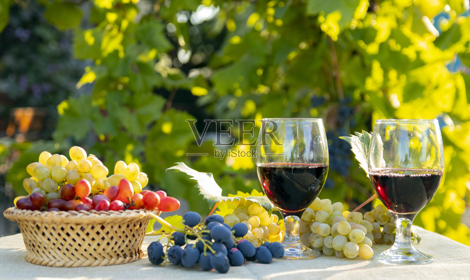 桌上和篮子里放着各式各样的新鲜葡萄和一杯葡萄酒。有选择性的重点。照片摄影图片