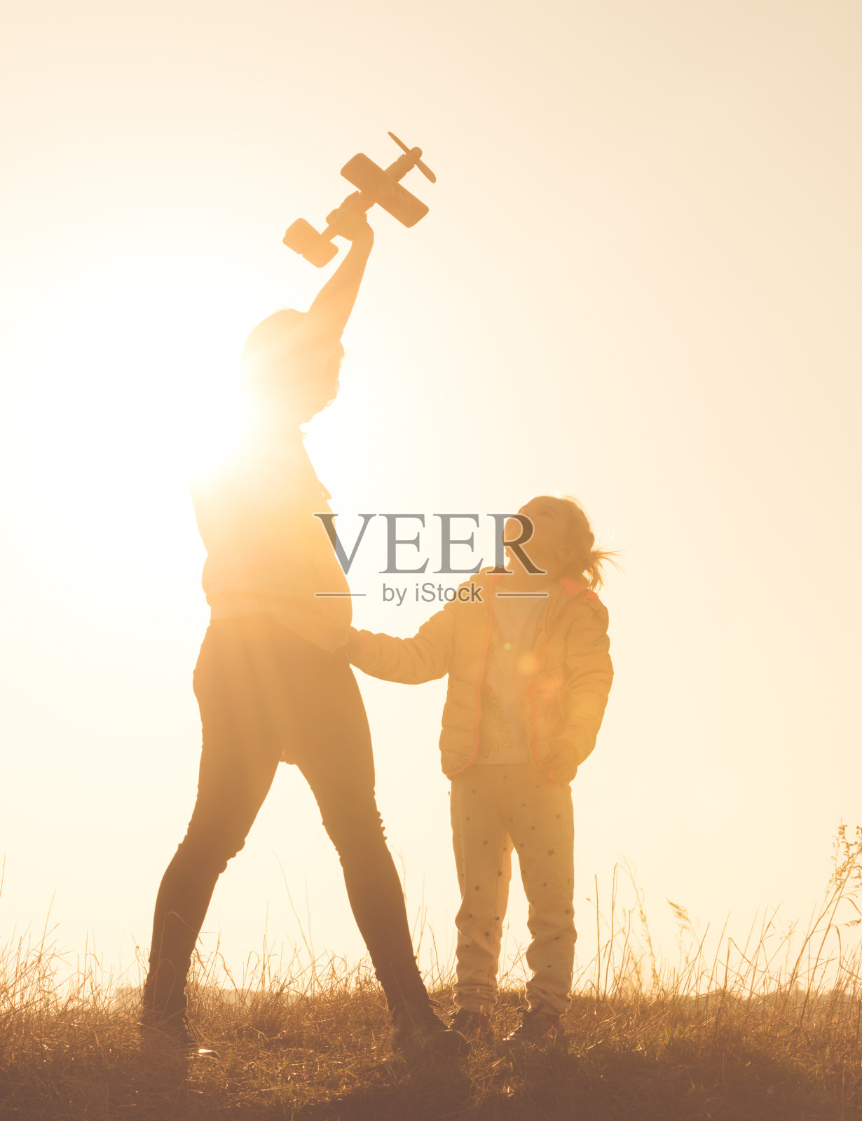 日落时分,母亲和女儿在田野里玩耍的剪影照片摄影图片