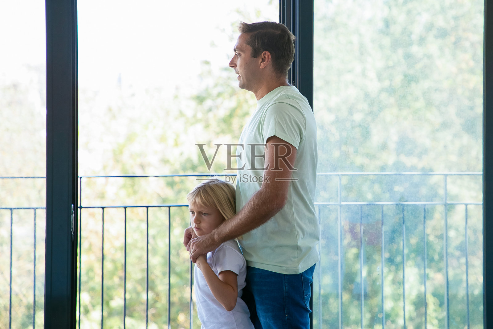 快乐的爸爸拥抱女儿,看着全景窗口照片摄影图片