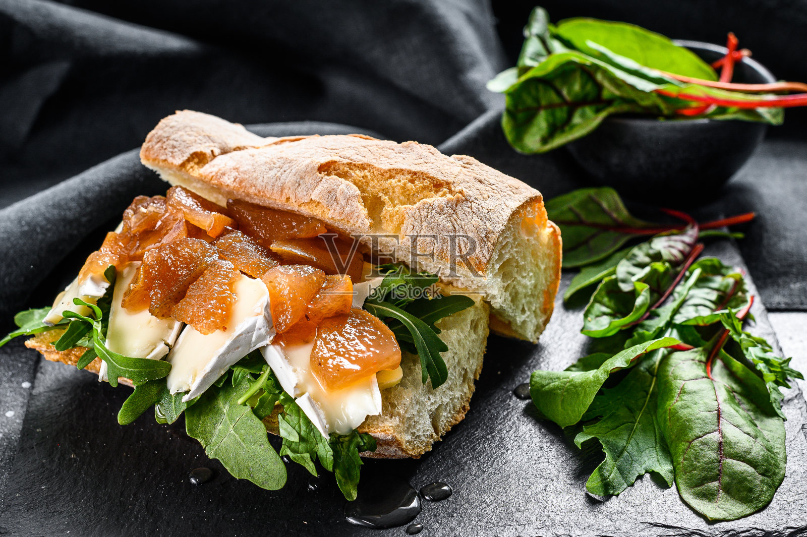 法式面包三明治配山羊奶酪,梨果酱,甜菜和菠菜。黑色背景。俯视图照片摄影图片